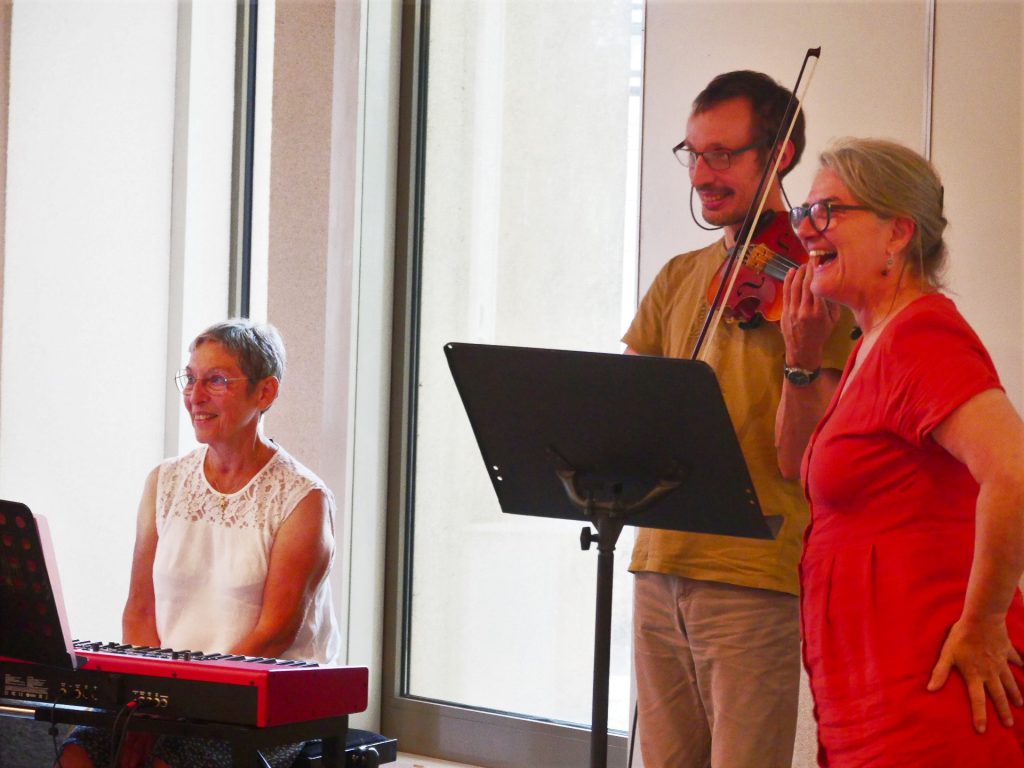 Hélène aux claviers, Guillaume au violon et Chantal qui les présente, tous sourires