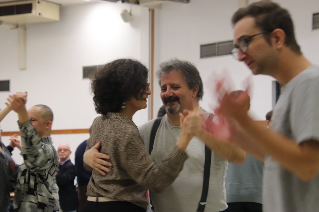 Un couple danse, et est entouré par d'autres personnes qui dansent autour d'eux