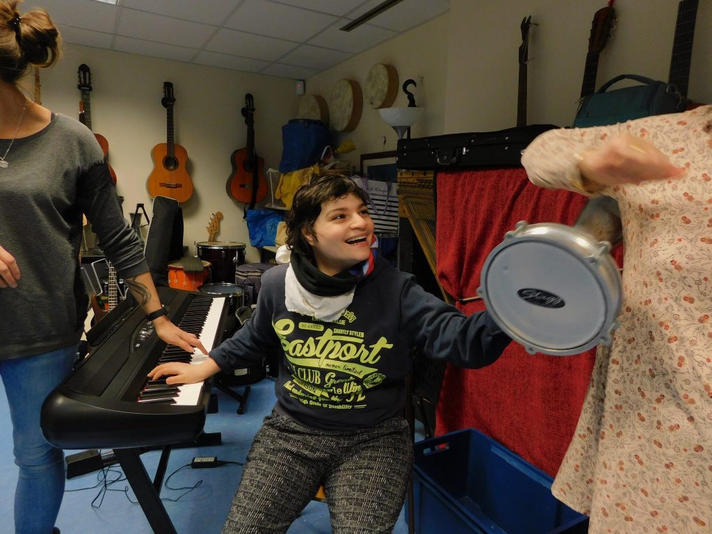 Une participante sourit et s'amuse avec une percussion et les claviers
